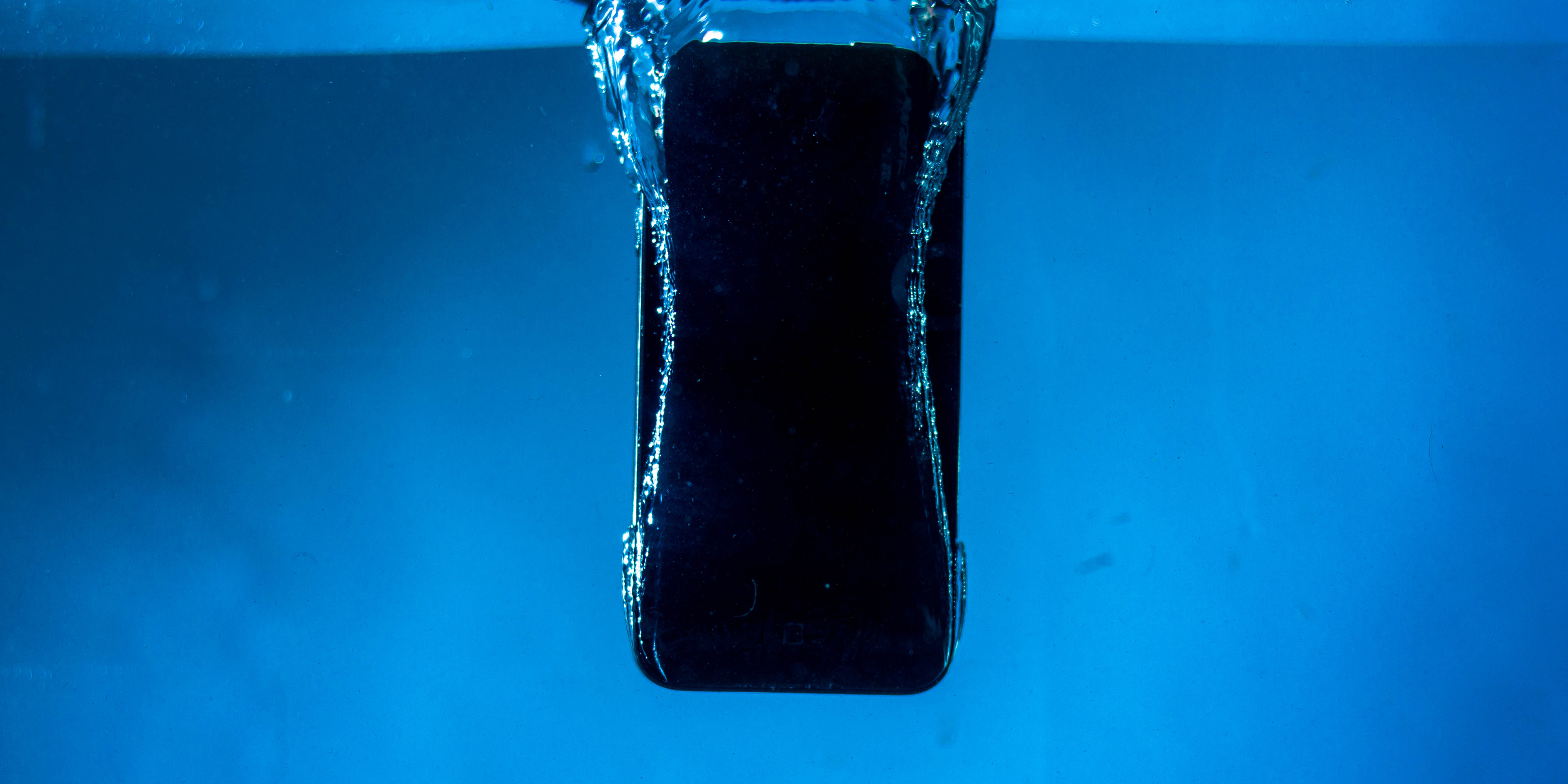 Smartphone sinking into water, representing water-damaged phone and urgent photo recovery needs