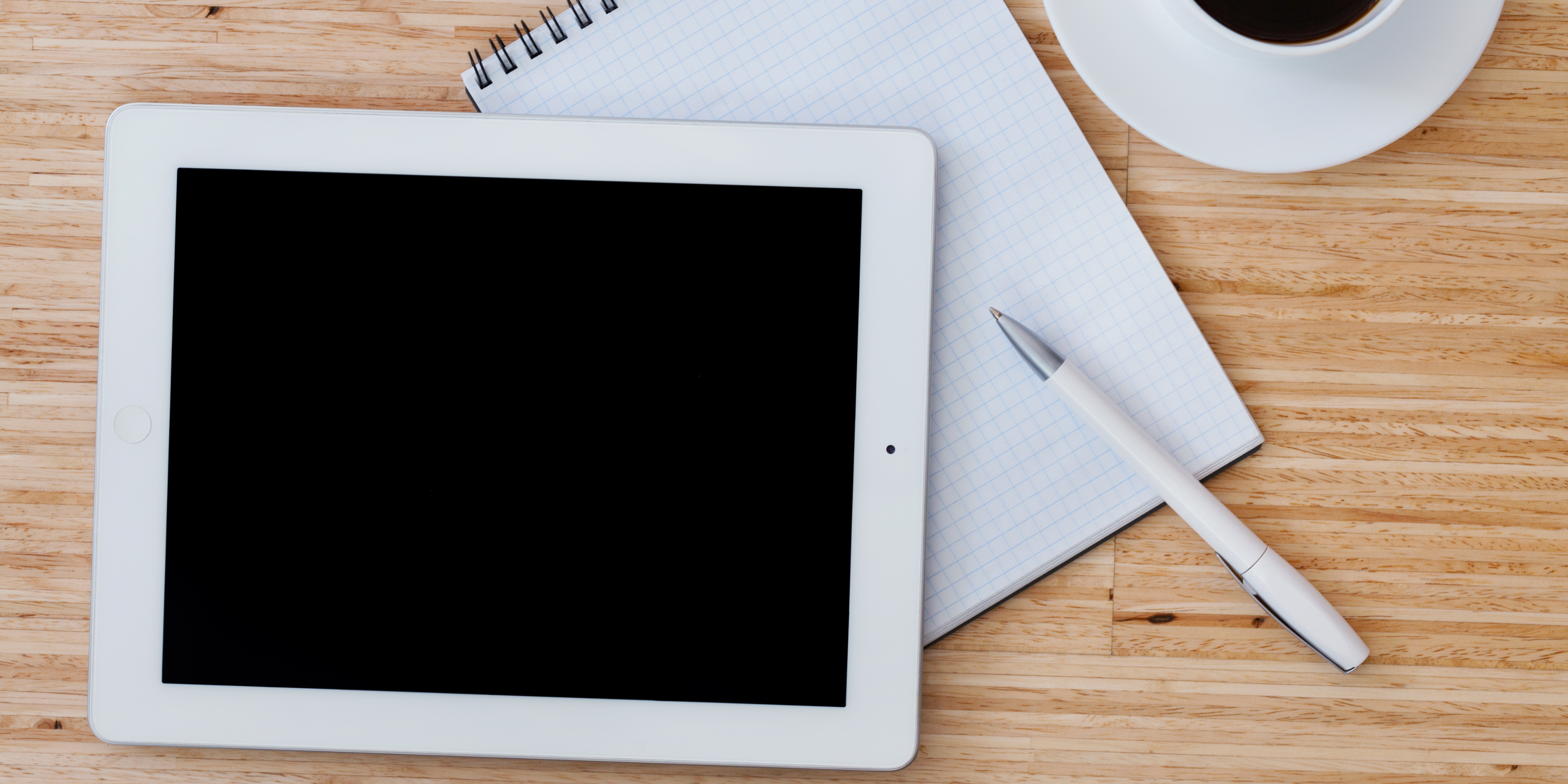 Tablet not turning on placed on a wooden desk with a notebook and pen – tablet charging issue illustration